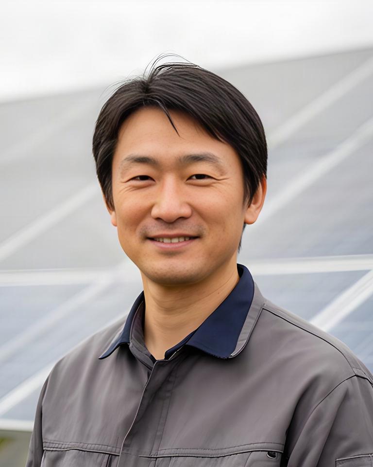 太陽光パネルを背景にしたShinano Solar Systems代表取締役の自然な表情
